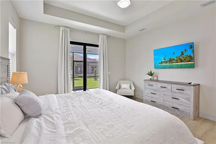 Bedroom featuring wood finished floors, access to outside, and a raised ceiling