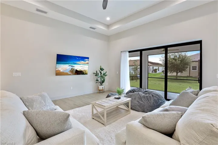 Living room with wood finished floors, recessed lighting, and a raised ceiling