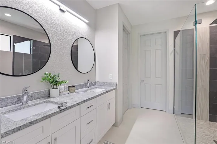 Bathroom featuring double vanity, walk in shower, and recessed lighting