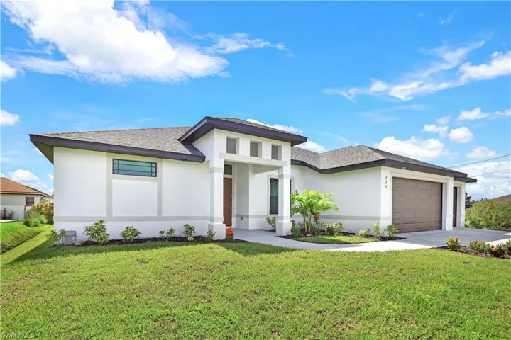 Prairie-style home featuring stucco siding, a front yard, a garage, and roof with shingles