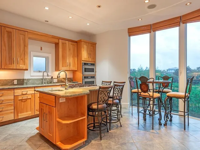 Luxury kitchen with gas cooktop, custom cabinetry, and ceiing to floor impact windows