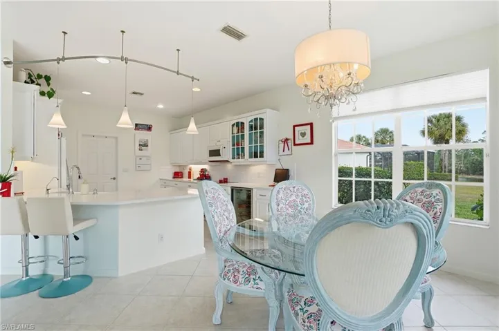 Dining space with wine cooler, light tile patterned floors, and hanging lights