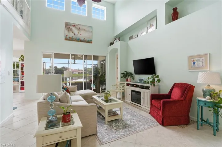 Living area with ceiling fan, light tile patterned flooring, a high ceiling, and arched walkways