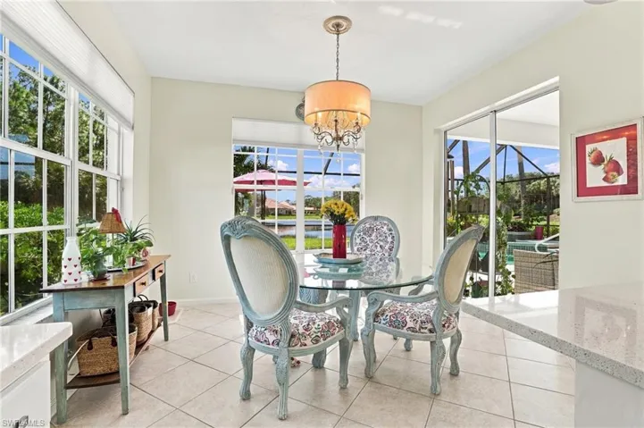 Bright, open space featuring tile flooring, a multi-light drum shade chandelier, abundant natural light from large windows, and floor-to-ceiling sliding glass doors