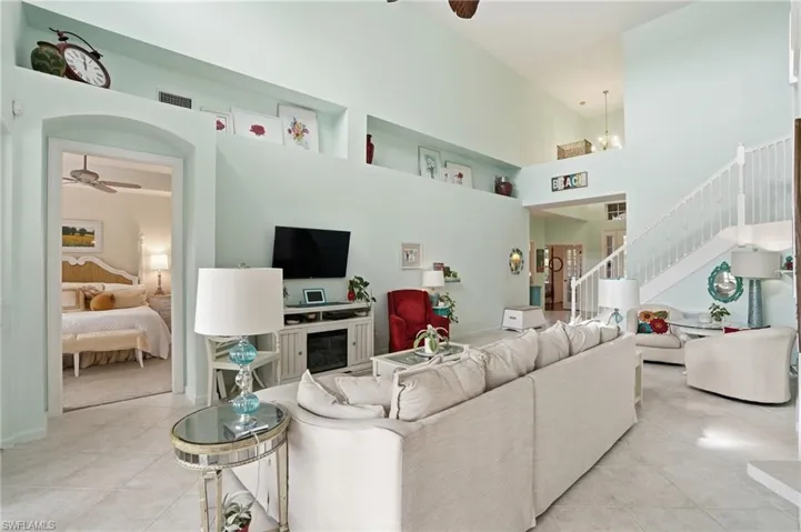 Living area featuring a ceiling fan, a high ceiling, light tile patterned floors, and a chandelier