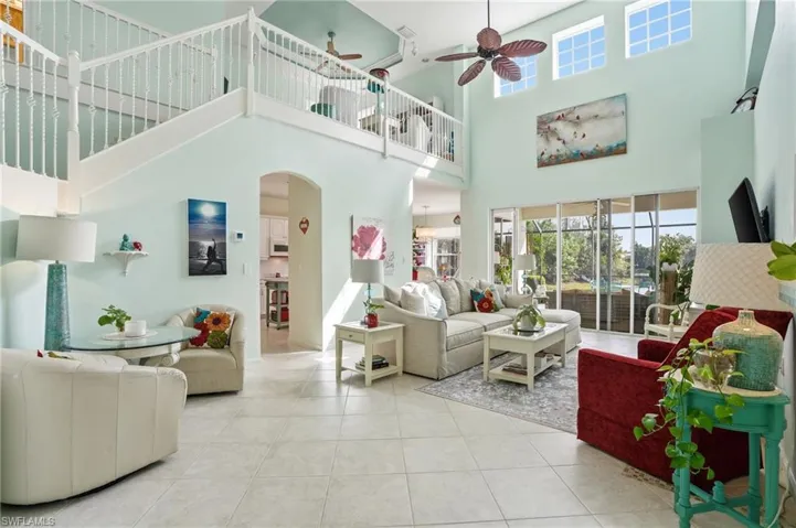 Living room featuring arched walkways, healthy amount of natural light, a ceiling fan, tile patterned floors, and a high ceiling