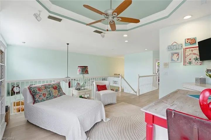 Bedroom featuring wood finished floors, ornamental molding, recessed lighting, ceiling fan, and a tray ceiling