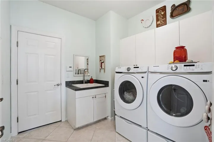 Laundry room featuring separate washer and dryer, cabinet space, and light tile patterned floors