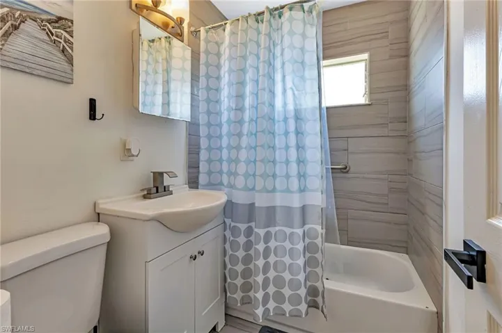Full bathroom with vanity, toilet, and shower / bath combo with shower curtain