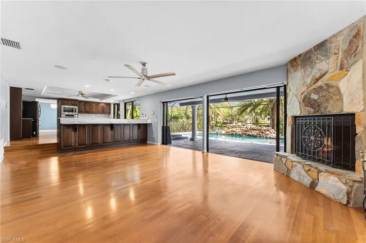 Unfurnished living room featuring ceiling fan, light wood finished floors, a stone fireplace, and recessed lighting