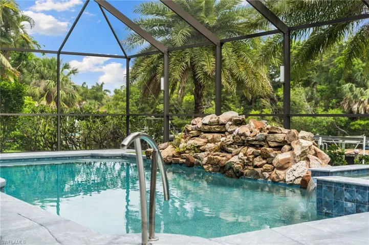 Swimming pool featuring a hot tub and glass enclosure