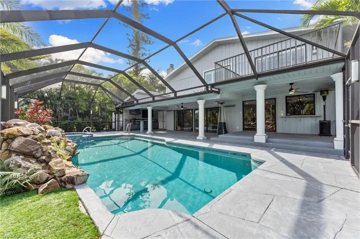 View of swimming pool featuring a ceiling fan, a patio, a pool with connected hot tub, and glass enclosure