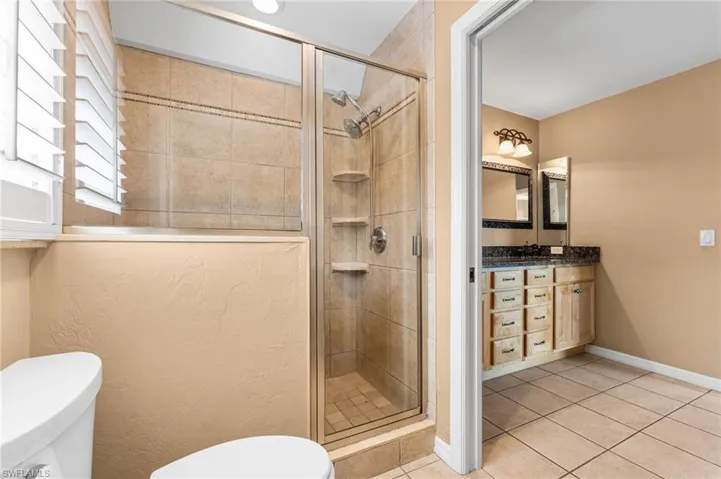 Bathroom with tile patterned floors, vanity, and a stall shower
