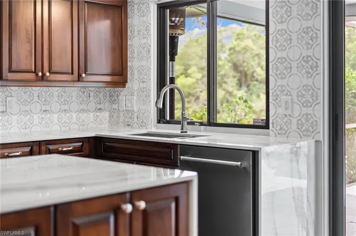 Kitchen featuring dishwasher, light countertops, and wallpapered walls