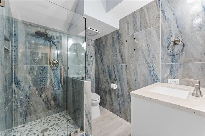 Full bath featuring tile walls, vanity, and a shower stall