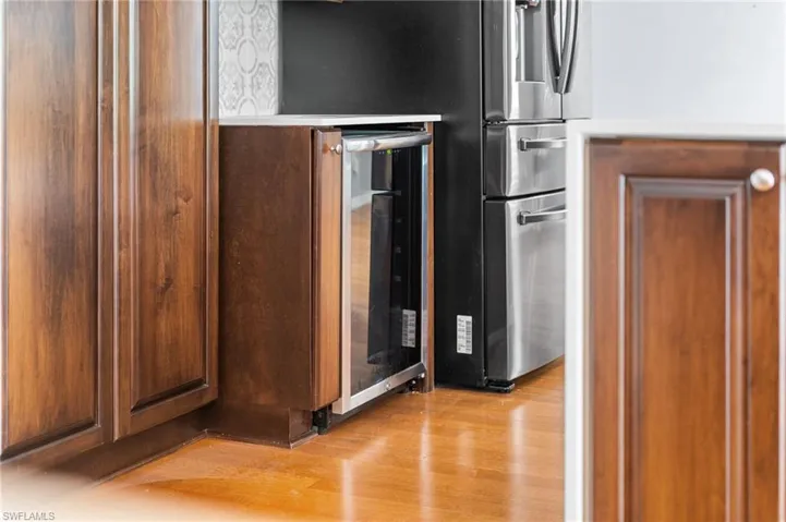 Kitchen view of light wood-style floors and beverage cooler