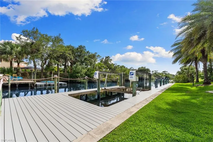 Dock featuring boat lift, a lawn, and a water view