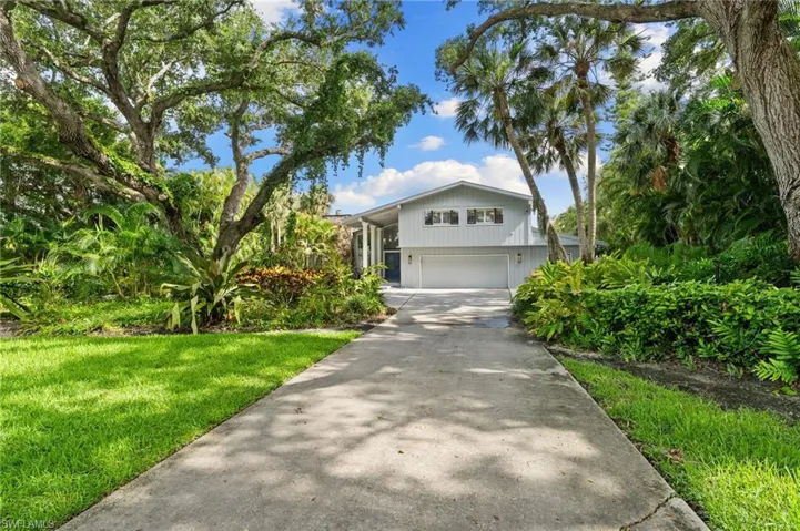 View of front of house featuring a garage, driveway, and a front lawn