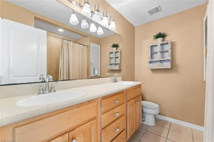 Full bathroom featuring double vanity, tile patterned floors, and a shower with shower curtain