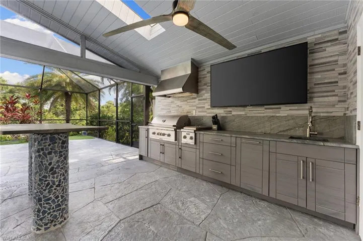 View of patio with an outdoor kitchen, ceiling fan, and a lanai