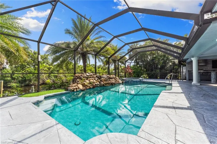View of swimming pool with a patio, a pool with connected hot tub, and glass enclosure