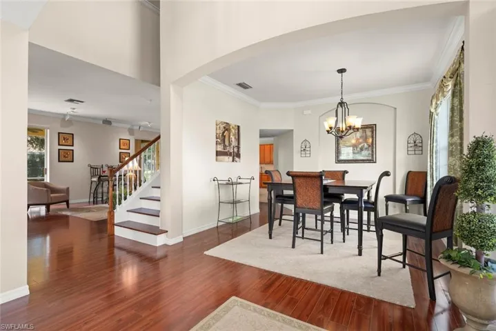 Foyer and formal dining room with laminate floors, ornamental molding, stairs, and arched walkways