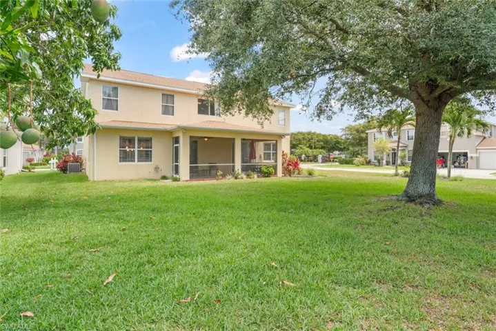 Back of house with stucco siding, a lawn, central AC units, and a screened lanai - plenty of room to add a pool!
