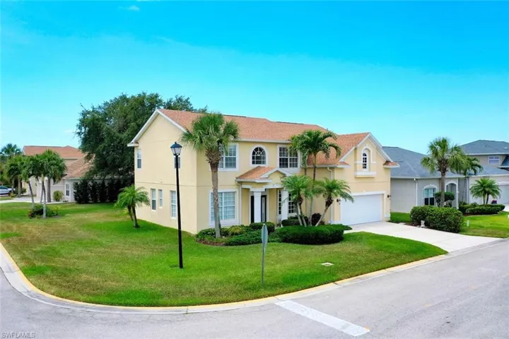 View of front of house with stucco siding, an attached two-car garage, driveway, and a large corner lot
