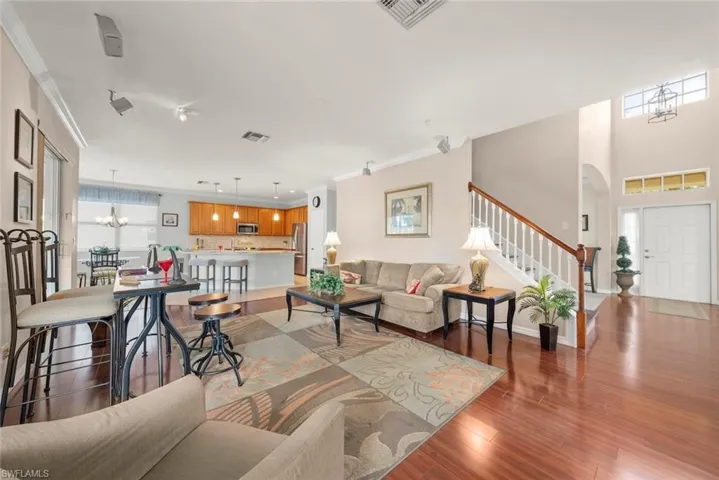 Family room featuring stairs, laminate flooring, crown molding, and a view of the entryway