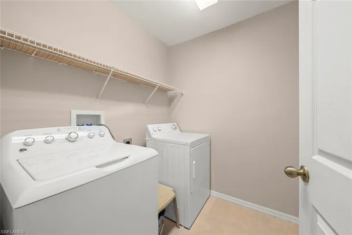 Laundry room with washer and dryer, baseboards, shelving, and light tile patterned flooring