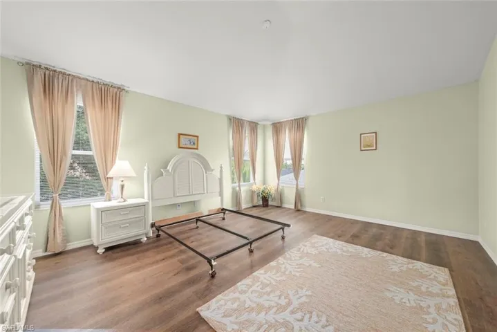 Primary bedroom featuring baseboards, laminate flooring, and multiple windows