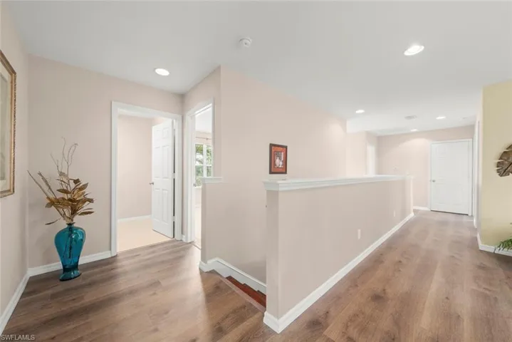 Hallway with staircase, laminate floors, baseboards, and recessed lighting