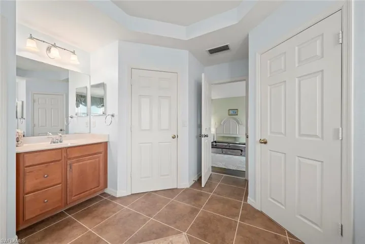 Primary bathroom featuring tile patterned floors, vanity, and two walk-in closets