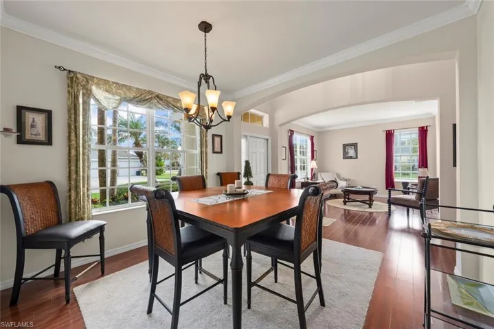 Formal dining room with a chandelier, arched walkways, laminate flooring, crown molding, and baseboards