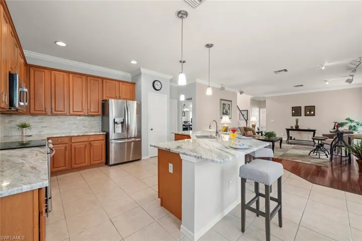 Kitchen featuring stainless steel appliances, a sink, ornamental molding, light tile patterned flooring, and backsplash