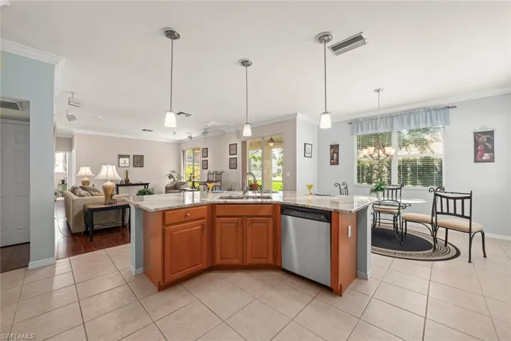 Kitchen with dishwasher, a sink, ornamental molding, and light tile patterned flooring