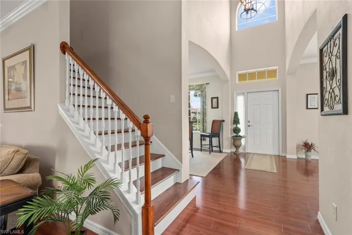 Foyer with arched walkways, plenty of natural light, a high ceiling, laminate floors, and stairway