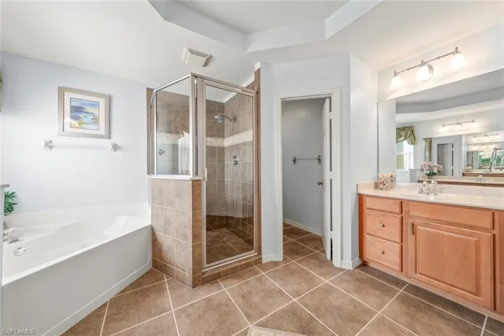 Primary bathroom featuring a shower stall, a garden tub, tile patterned flooring, and vanity