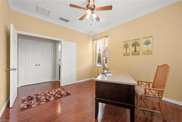 Home office, library, or den area with laminate floors, a ceiling fan, baseboards, crown molding, and recessed lighting