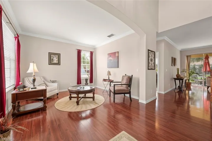 Formal living room or sitting room featuring plenty of natural light, arched walkways, laminate floors, and crown molding