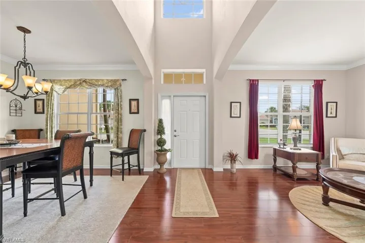 Entryway with ornamental molding, healthy amount of natural light, laminate floors, and baseboards