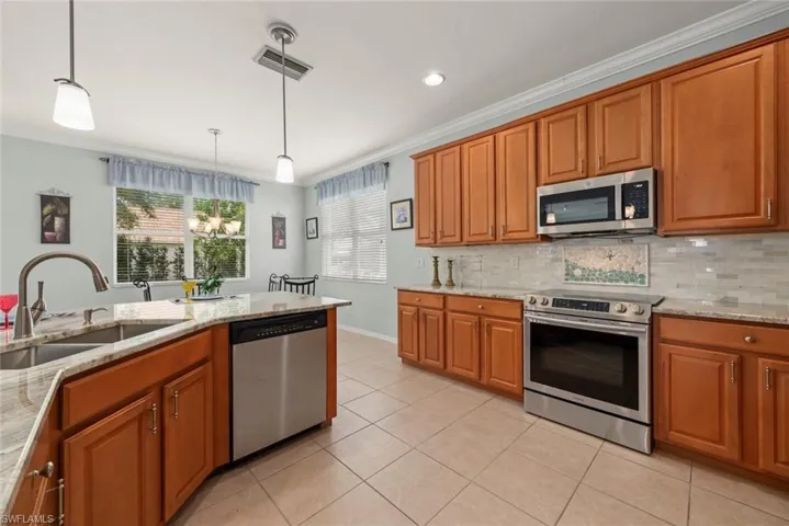 Kitchen featuring stainless steel appliances, a sink, ornamental molding, cabinets, and tiled backsplash