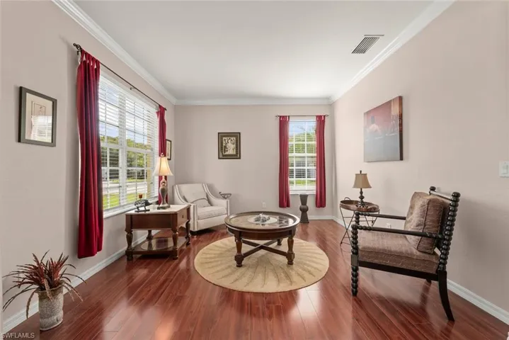 Formal living room or sitting room with ornamental molding, baseboards, and laminate flooring