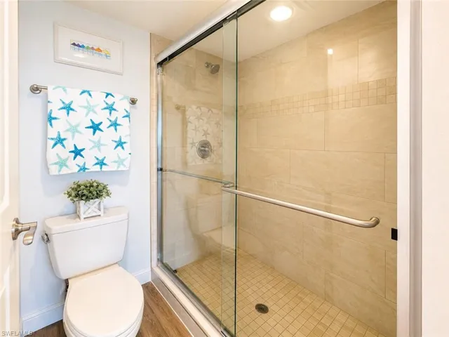 Glass-enclosed shower with full-height tile surround featuring a decorative mosaic accent band