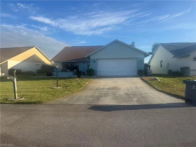 Ranch-style house with a front lawn, concrete driveway, and a garage
