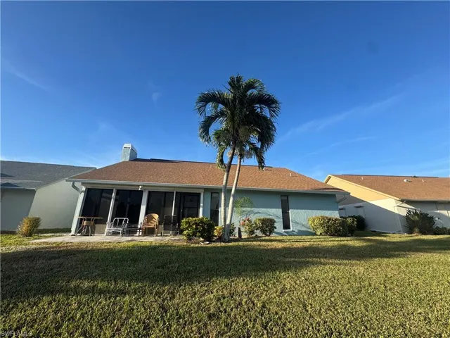 View of front facade with a front lawn, a sunroom, and a chimney