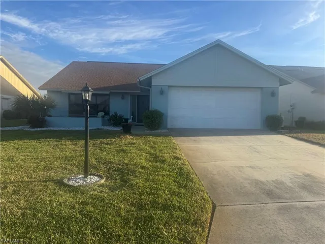 Single story home featuring a garage, a front yard, concrete driveway, and stucco siding