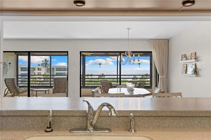Kitchen with pendant lighting, a chandelier, healthy amount of natural light, and light stone counters