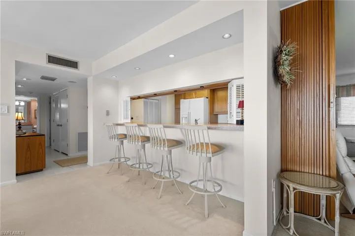 Kitchen with brown cabinets, a breakfast bar area, light carpet, light countertops, and recessed lighting
