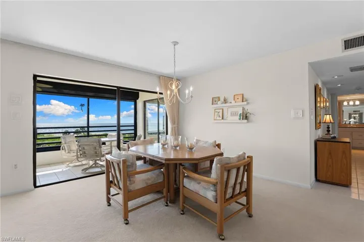 Dining room featuring a chandelier, light carpet, light tile patterned floors, and a water view